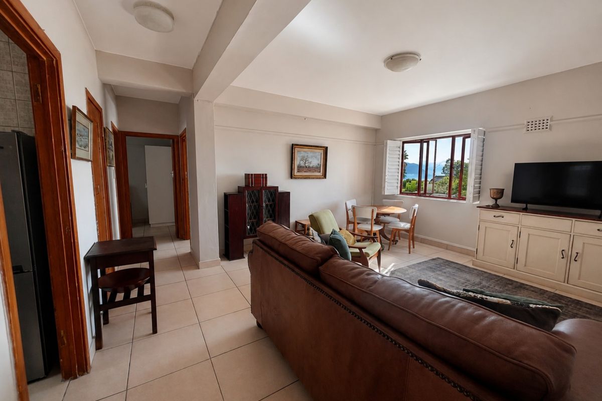 Spacious living area featuring tiled flooring, natural light through casement windows, and neutral wall finishes, offering a comfortable and functional layout.