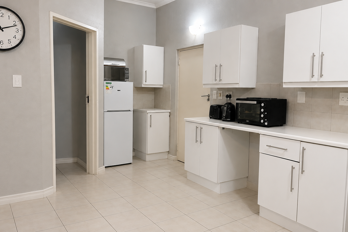 A clean, functional kitchen featuring white cabinetry, tiled flooring, and a tiled backsplash, offering a bright and well-maintained workspace.