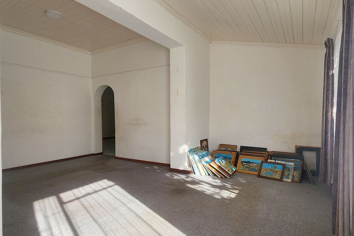 A spacious, vacant living area featuring a classic timber tongue and groove ceiling, an arched doorway, and neutral wall finishes.