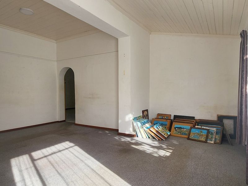 A spacious, vacant living area featuring a classic timber tongue and groove ceiling, an arched doorway, and neutral wall finishes.