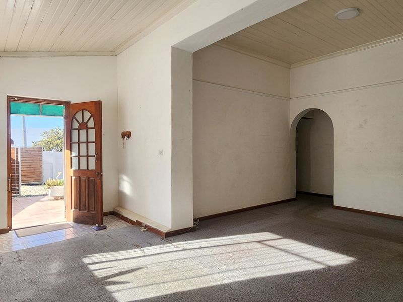 An empty living room featuring a timber tongue and groove ceiling, an arched doorway, and direct access to an outdoor patio area.