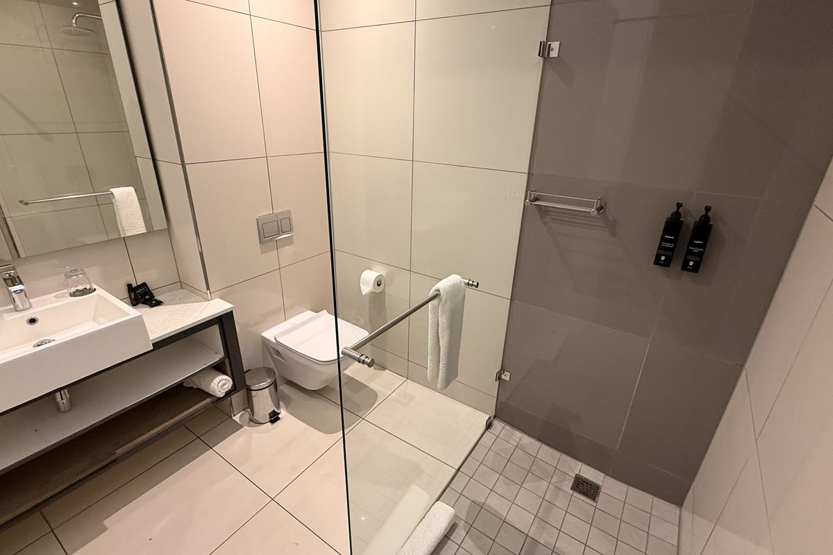 Modern bathroom featuring a wall-mounted basin, wall-hung toilet with concealed cistern, and a spacious walk-in shower with a glass screen.