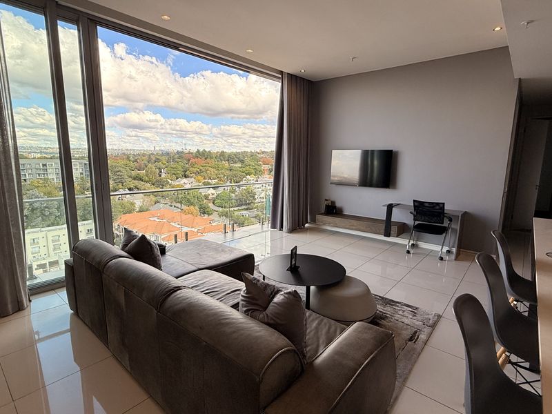 Modern open-plan living area featuring floor-to-ceiling glass doors, sleek porcelain tiling, and expansive views from the private balcony.