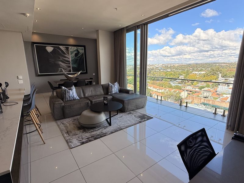 Modern open-plan living area featuring high-end finishes, floor-to-ceiling glass doors, and expansive panoramic views from the penthouse level.