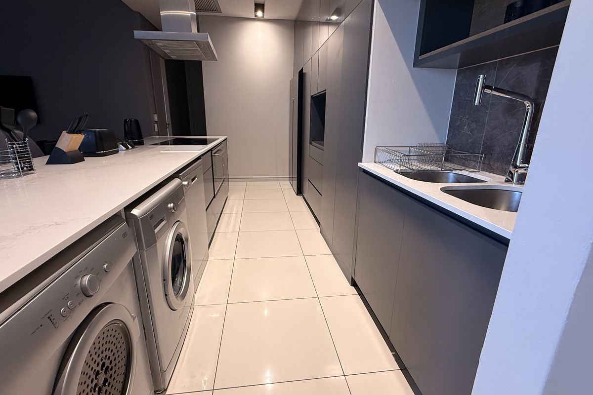 Modern kitchen featuring sleek dark cabinetry, quartz countertops, integrated appliances, and high-quality finishes in a contemporary penthouse setting.