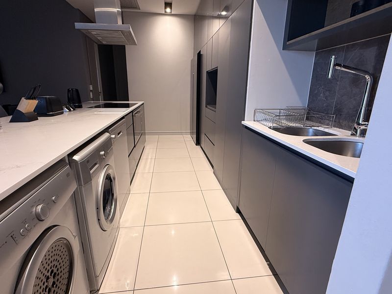 Modern kitchen featuring sleek dark cabinetry, quartz countertops, integrated appliances, and high-quality finishes in a contemporary penthouse setting.
