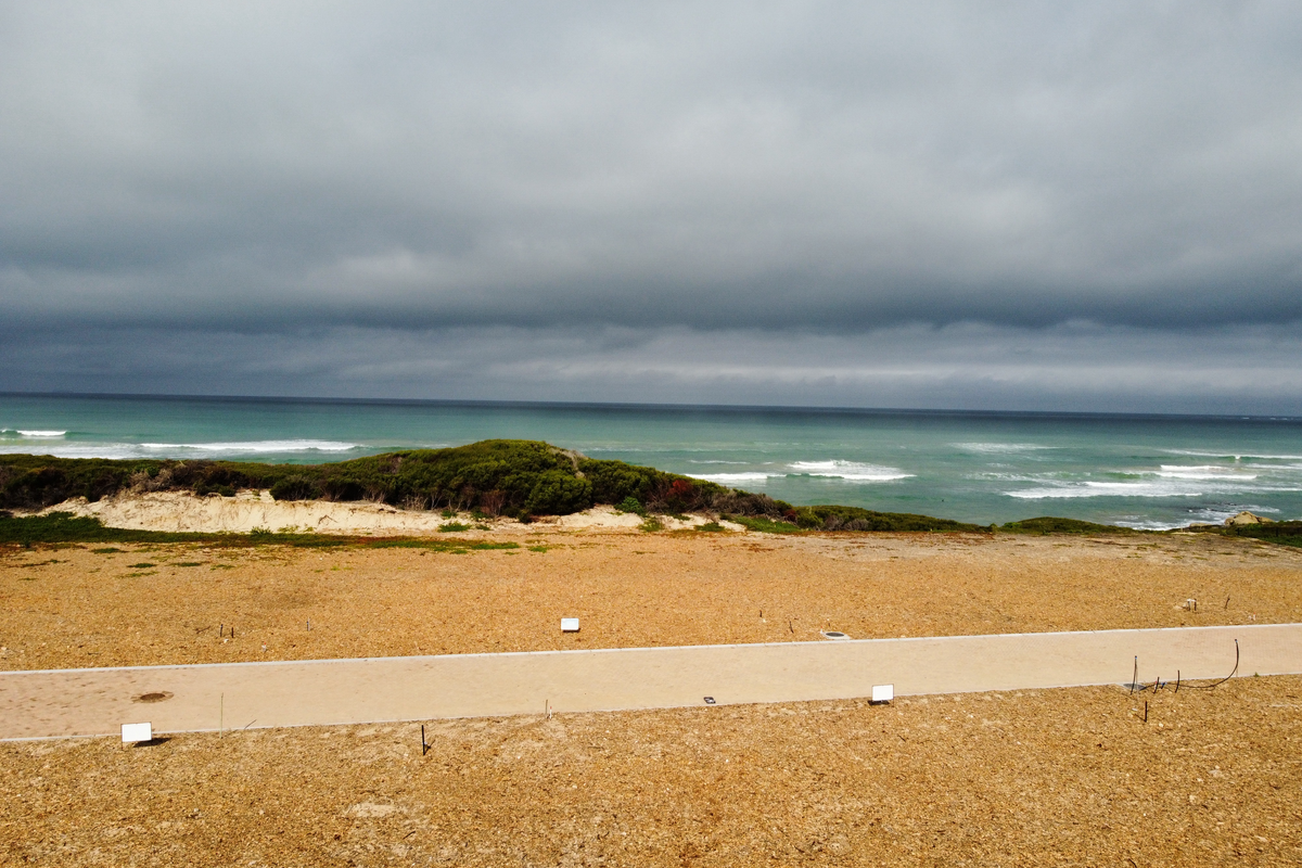 A scenic view of the coastline featuring natural dunes and ocean waves, showcasing the property's prime location.