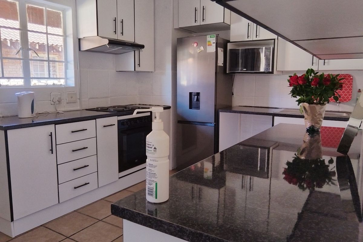 A functional kitchen featuring white cabinetry, dark granite countertops, a gas hob, built-in oven, and tiled flooring.