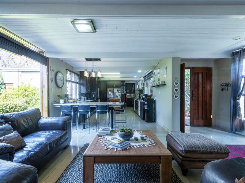 Spacious open-plan living area featuring a modern kitchen with island seating, tiled floors, and large sliding doors providing seamless access to the garden.