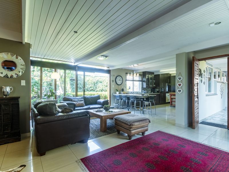 Spacious open-plan living and kitchen area featuring tiled floors, timber ceilings, and large sliding glass doors providing seamless access to the garden.