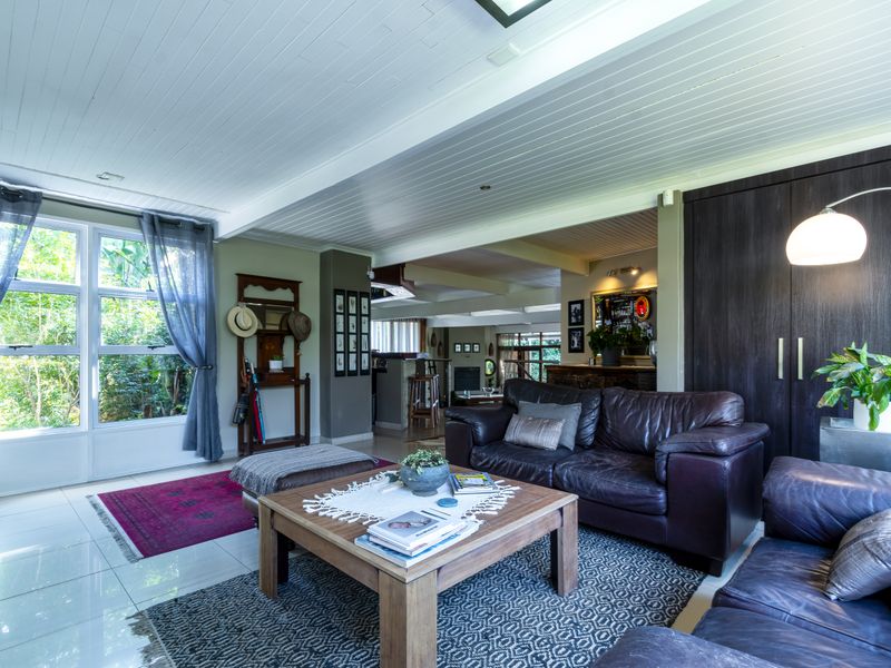 Spacious open-plan living area featuring tiled floors, a distinctive tongue and groove ceiling, and large windows that provide ample natural light.