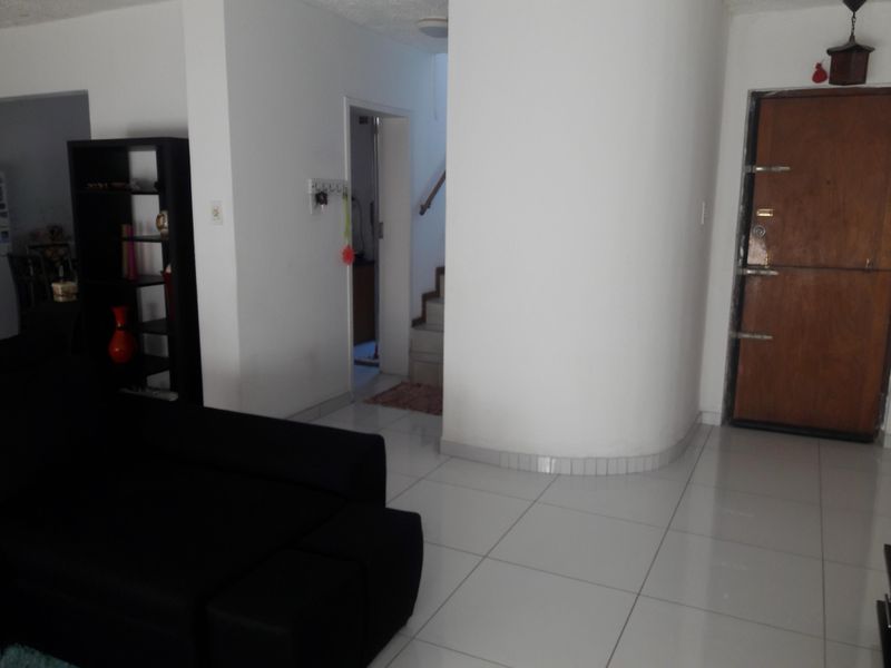 Entrance area featuring white tiled flooring, a distinctive curved wall, and a solid wood front door leading to an internal staircase.