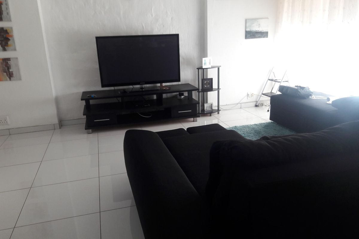A living room area featuring white tiled flooring and neutral walls, providing a bright and functional space for relaxation.