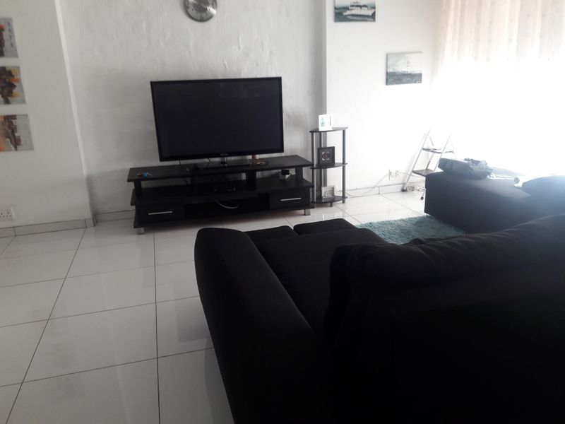 A living room area featuring white tiled flooring and neutral walls, providing a bright and functional space for relaxation.