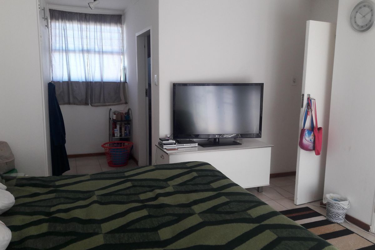 A bedroom featuring tiled flooring and a window, providing a functional space with neutral wall finishes.