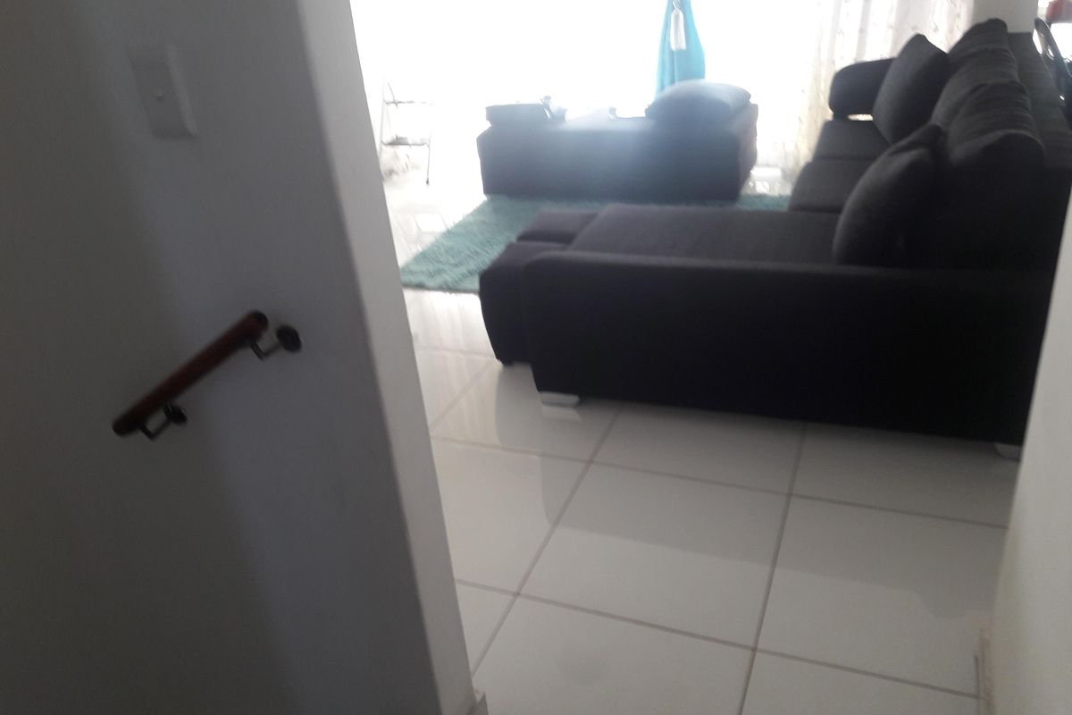 A view from a staircase looking into a living room area featuring large format floor tiles.