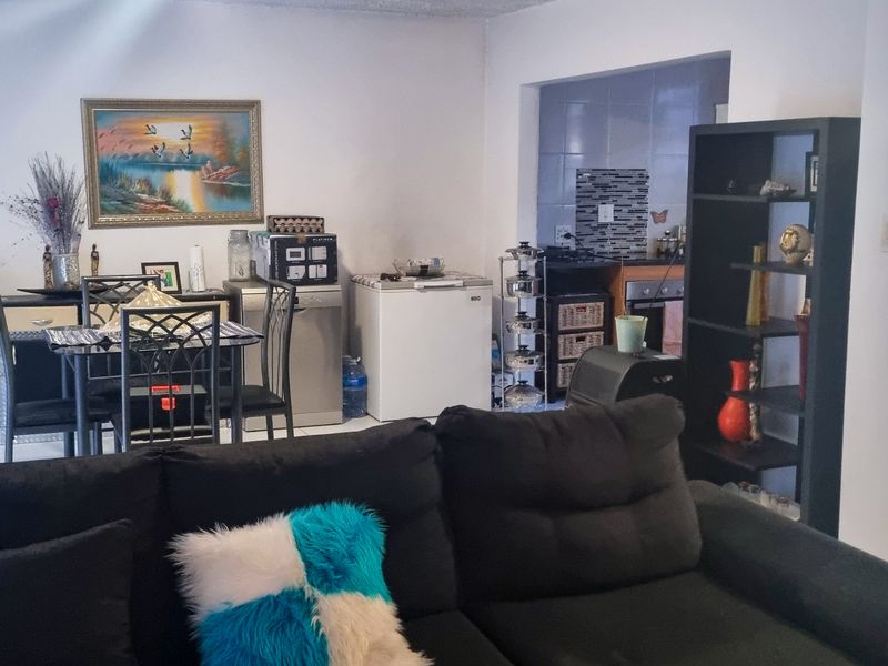 Open plan living and dining area featuring tiled floors and a semi-open kitchen with built-in cabinetry and oven.