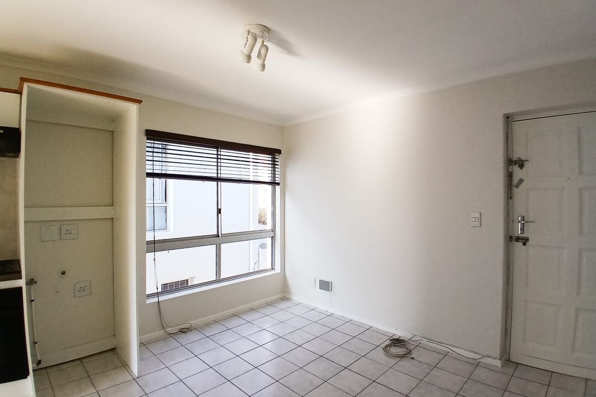 An empty kitchen area featuring tiled flooring, built-in cabinetry, and a security door, offering a blank canvas for potential updates.