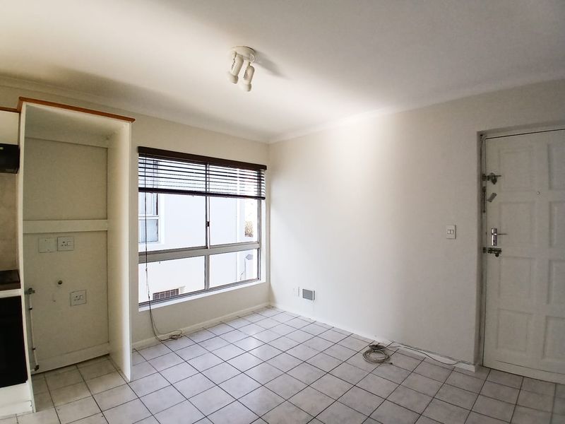 An empty kitchen area featuring tiled flooring, built-in cabinetry, and a security door, offering a blank canvas for potential updates.