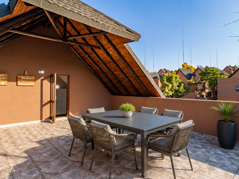 Spacious covered balcony featuring tiled flooring and an exposed timber roof structure, offering an open-air outdoor living space.
