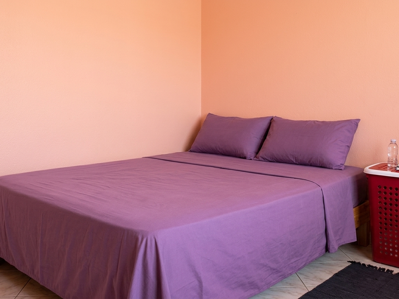 A simple bedroom featuring tiled flooring and peach-colored walls, providing a functional and neutral space.