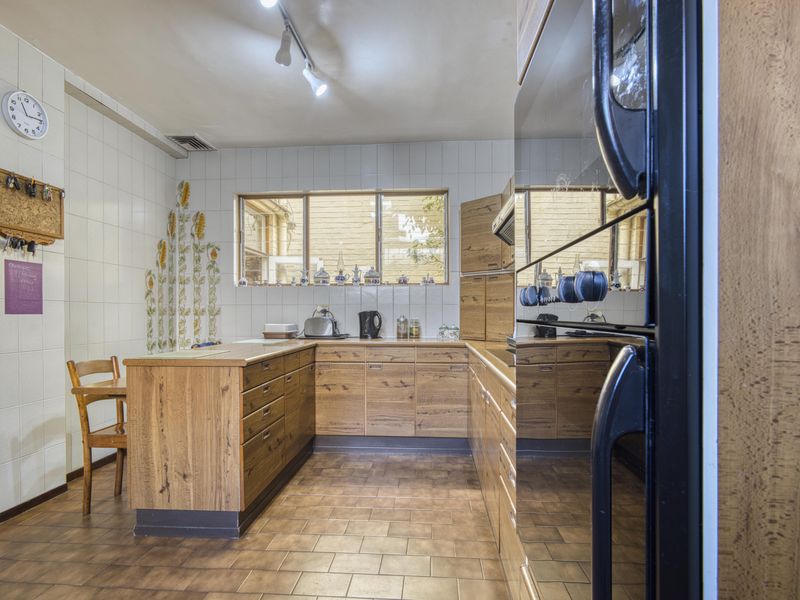 A functional kitchen featuring wooden cabinetry, tiled flooring, and a tiled backsplash with built-in oven and track lighting.