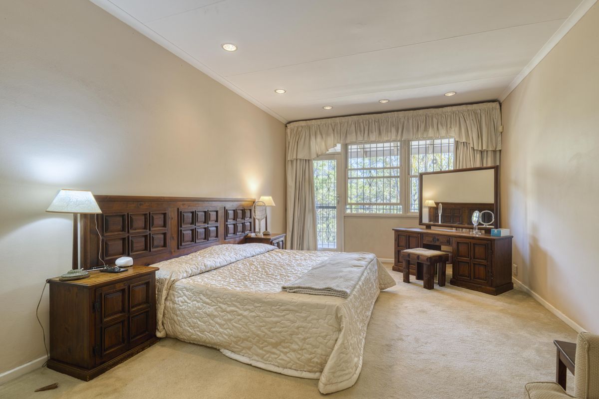 Spacious bedroom featuring neutral carpeting, recessed downlighting, and direct access to an outdoor area through a secure glass door.