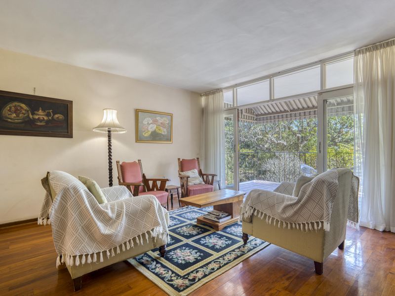 A bright living room featuring polished hardwood flooring and large sliding glass doors that provide access to an outdoor balcony area.