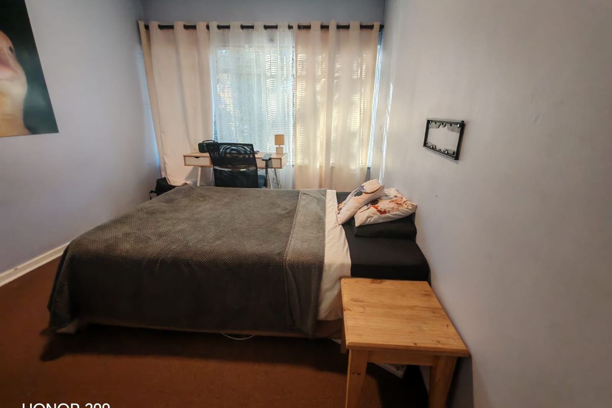 A standard bedroom featuring carpeted flooring and window treatments, providing a functional space for rest.