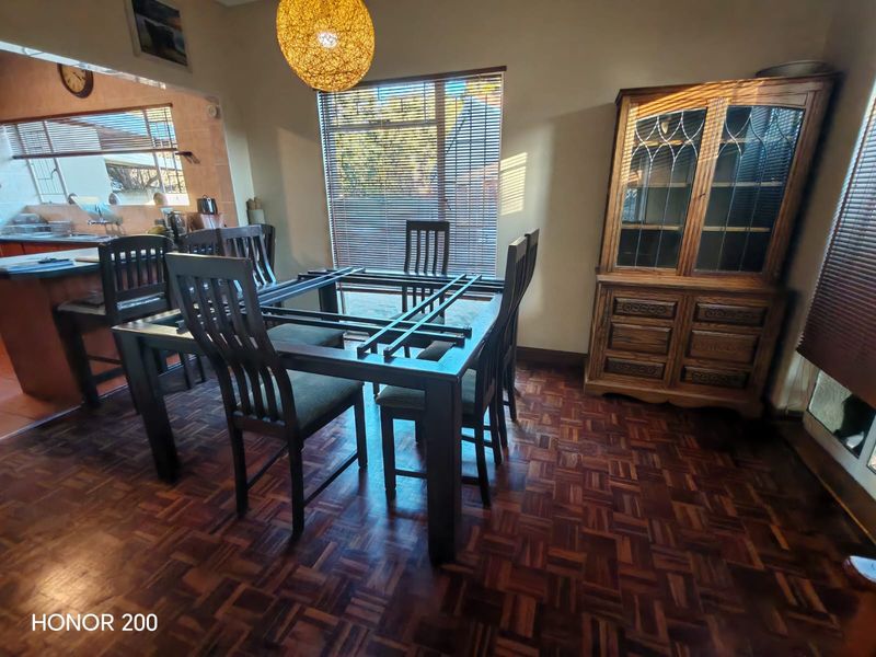 Open plan dining area featuring parquet flooring and venetian blinds, seamlessly connected to the adjacent kitchen space.