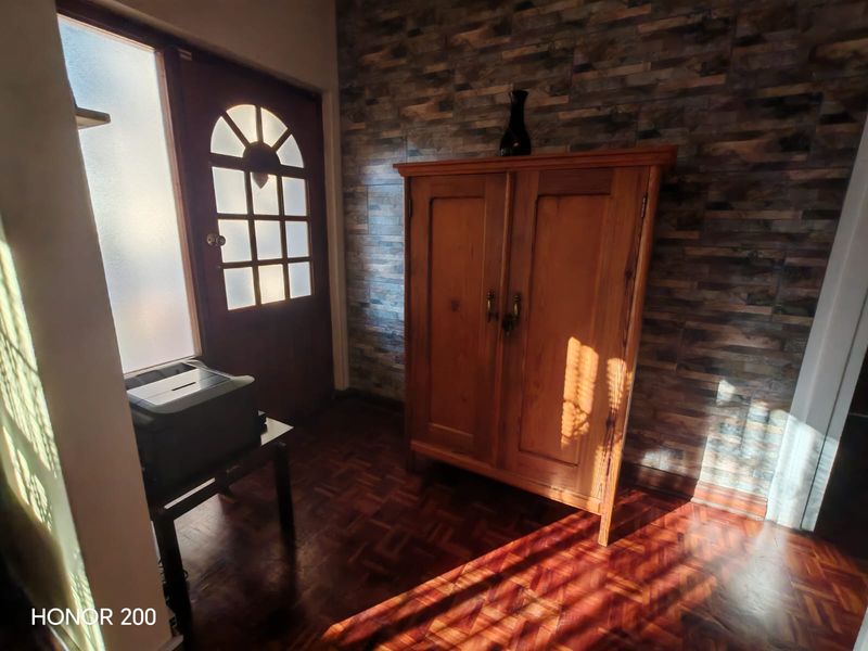 Entrance area featuring parquet flooring, a stone veneer feature wall, and a timber front door with glass inserts.