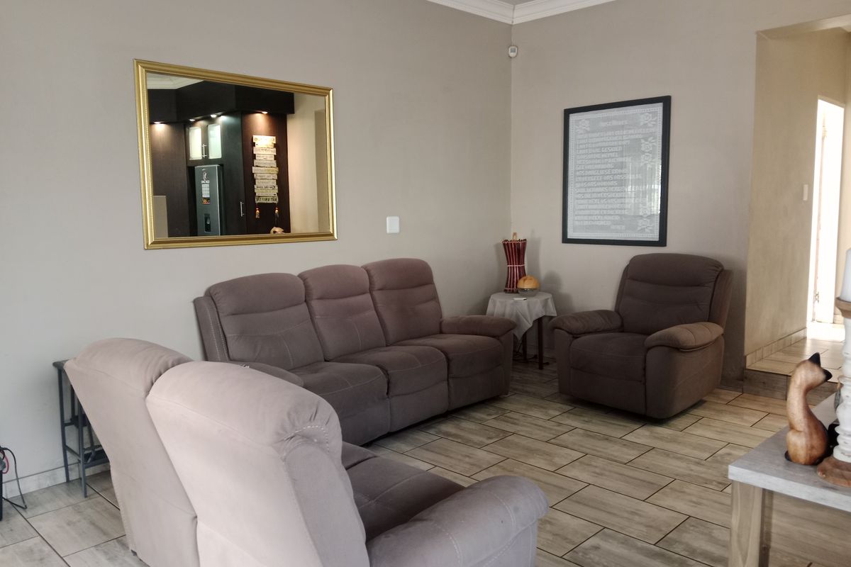 A comfortable living room featuring neutral wall tones, tiled flooring, and decorative coving, providing a functional and inviting space for relaxation.