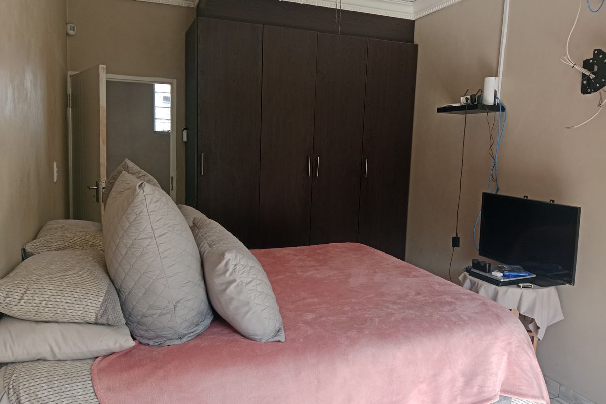 A bedroom featuring dark wood built-in cupboards and decorative crown molding, providing functional storage space.