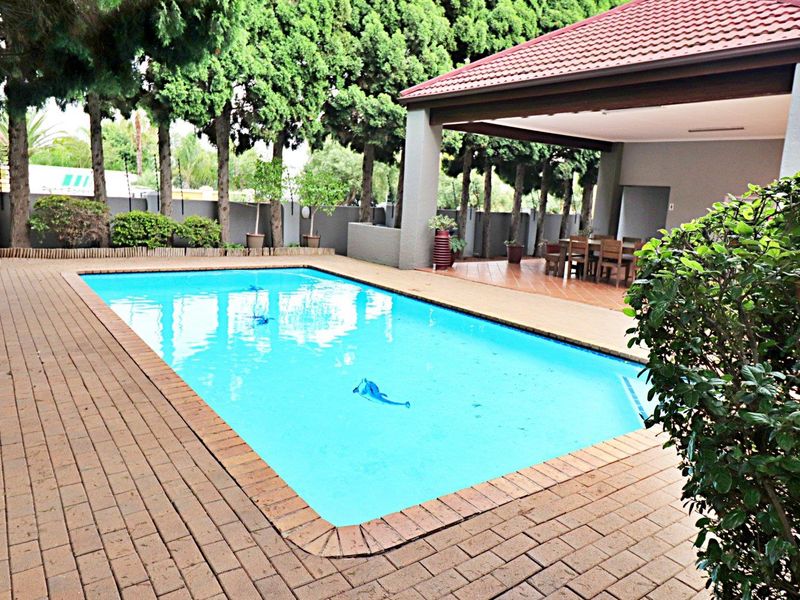 A well-maintained outdoor area featuring a swimming pool and a spacious covered patio, ideal for outdoor entertaining and relaxation.