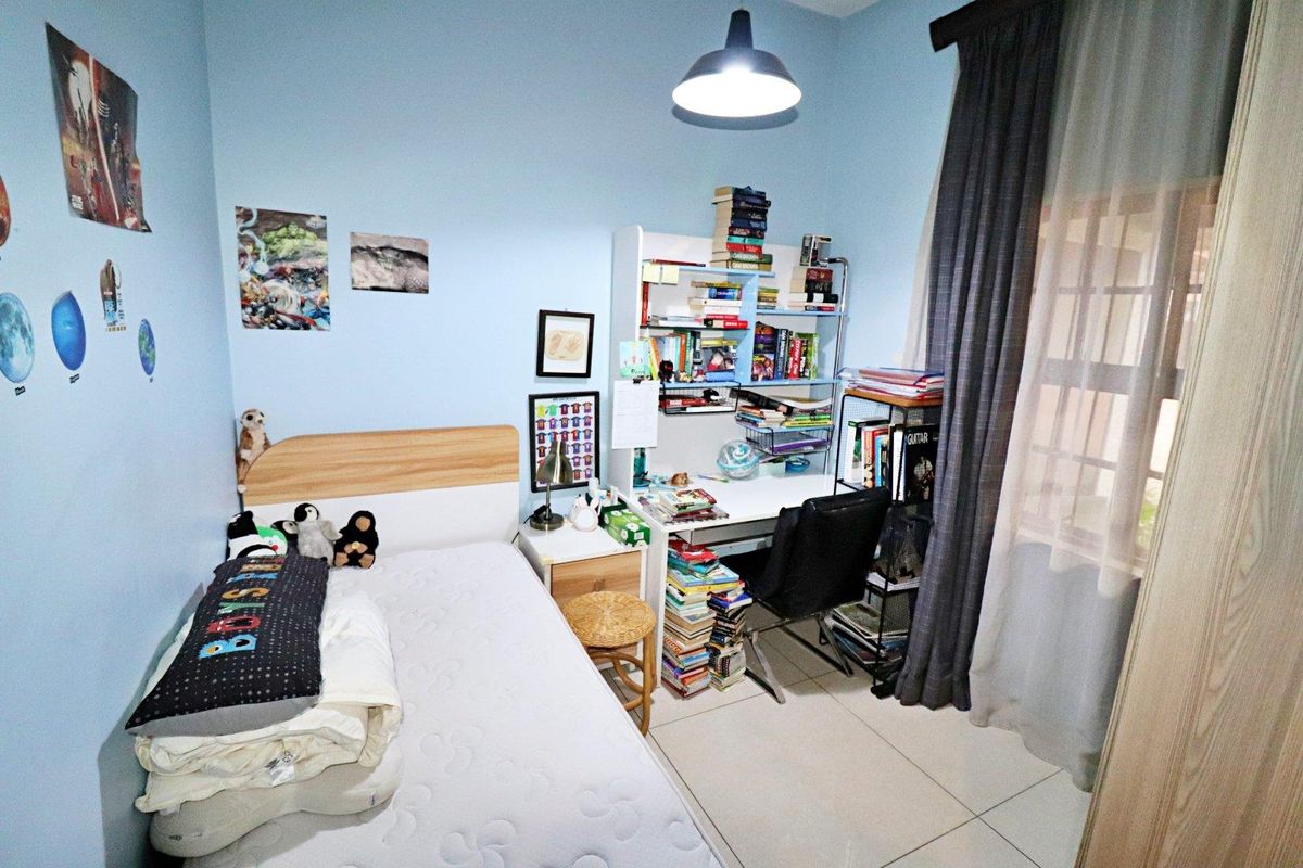 A functional bedroom featuring tiled flooring and a central pendant light fixture, providing a practical space for rest and study.