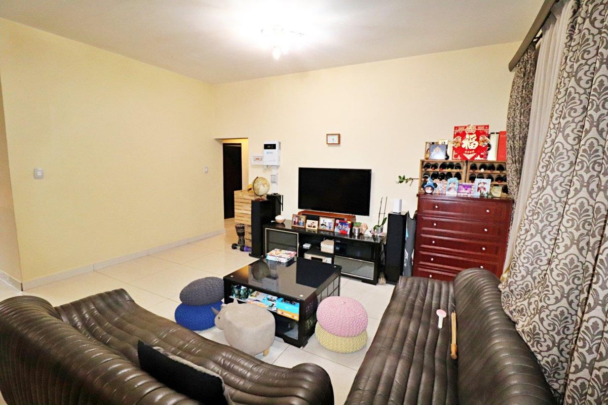 A functional living room featuring tiled flooring and neutral wall finishes, providing a comfortable space for relaxation and entertainment.