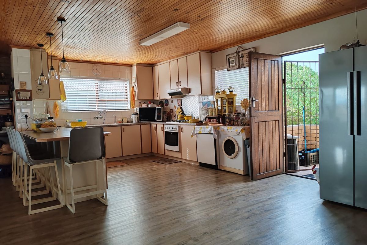 Spacious kitchen featuring timber ceilings, laminate flooring, a central island, and direct access to an outdoor area through a secure door.