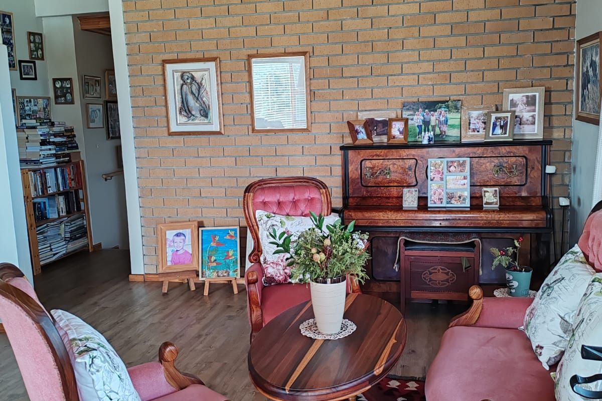 A cozy living room featuring an exposed brick feature wall, warm timber ceiling, and durable laminate flooring.