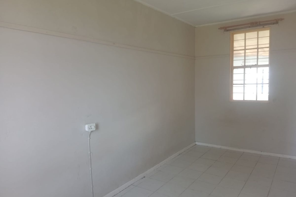 An empty bedroom featuring tiled flooring, a window with security bars, and neutral wall finishes, providing a blank canvas for potential updates.