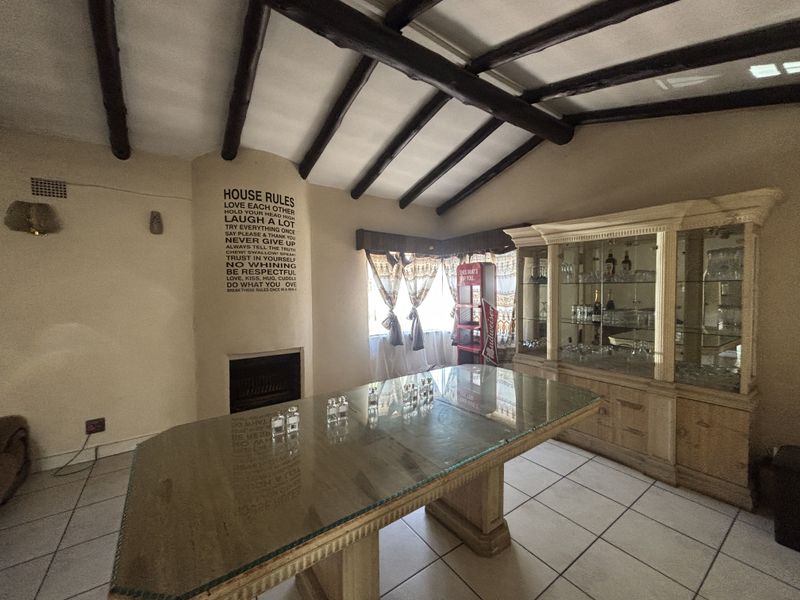 Living room featuring exposed timber ceiling beams, tiled flooring, and a built-in fireplace, offering a rustic aesthetic with potential for modern updates.