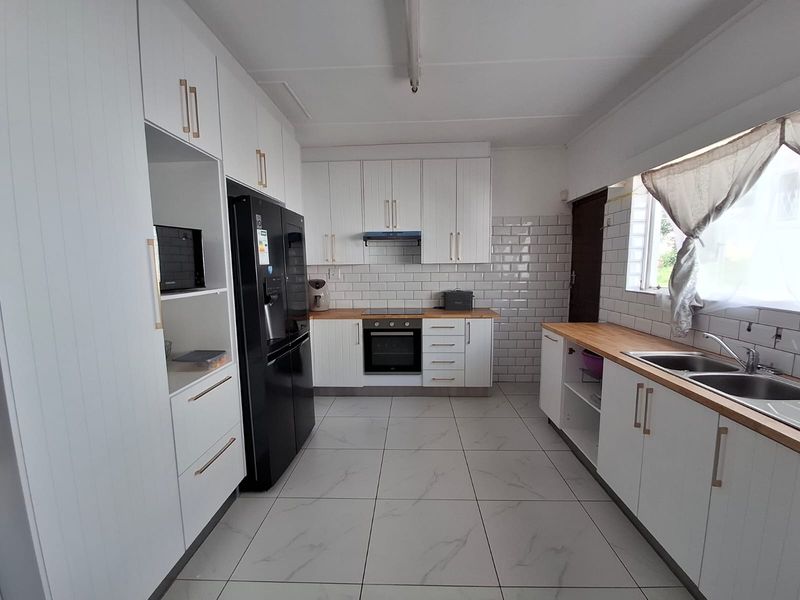 Modern kitchen featuring white cabinetry, subway tile backsplash, wooden countertops, and integrated appliances, offering a clean and functional workspace.