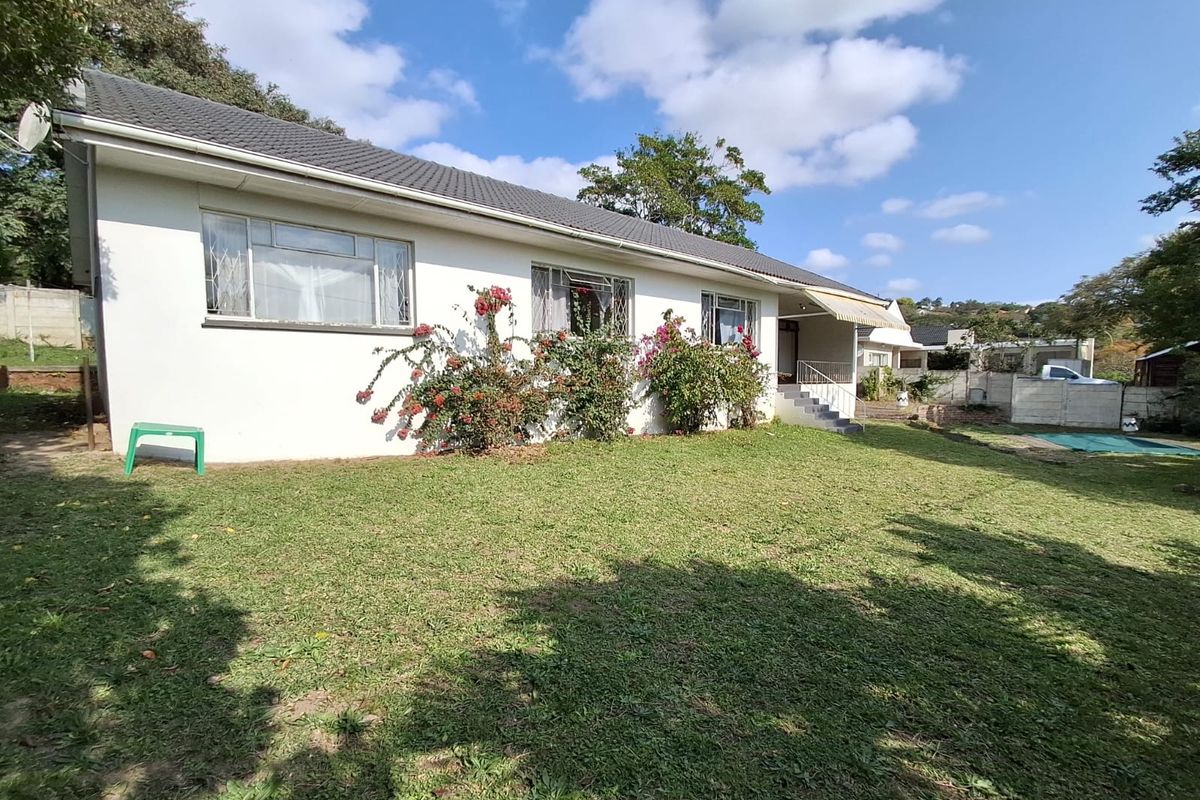 Rear view of the house featuring a tiled roof, concrete steps with metal railings, and a lawn area.