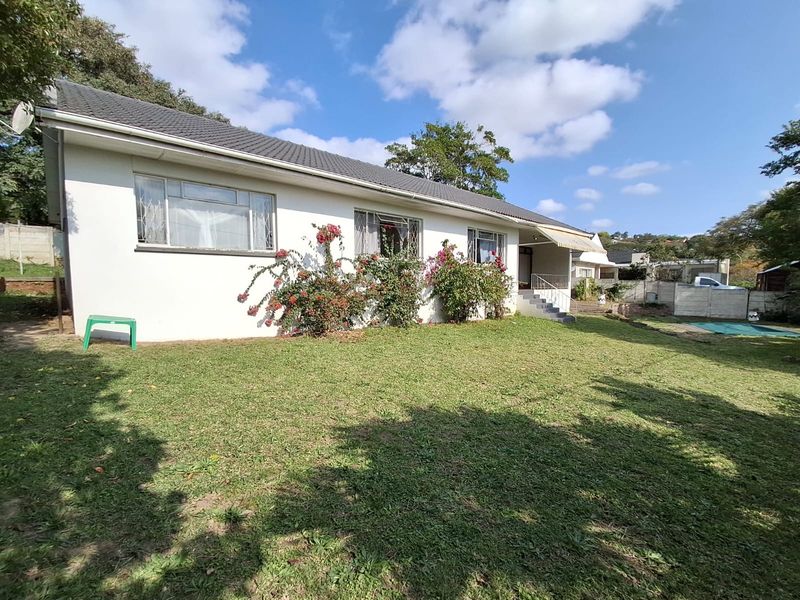 Rear view of the house featuring a tiled roof, concrete steps with metal railings, and a lawn area.