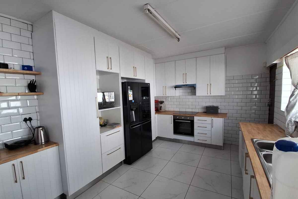 Modern kitchen featuring white cabinetry, subway tile backsplash, wooden countertops, built-in oven, extractor fan, and tiled flooring.