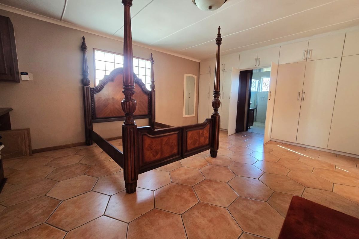 Spacious bedroom featuring built-in cupboards, hexagonal tiled flooring, and direct access to an en-suite bathroom.