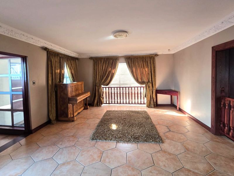 Spacious living area featuring hexagonal floor tiles, decorative ceiling cornicing, and a wooden balustrade overlooking the lower level.