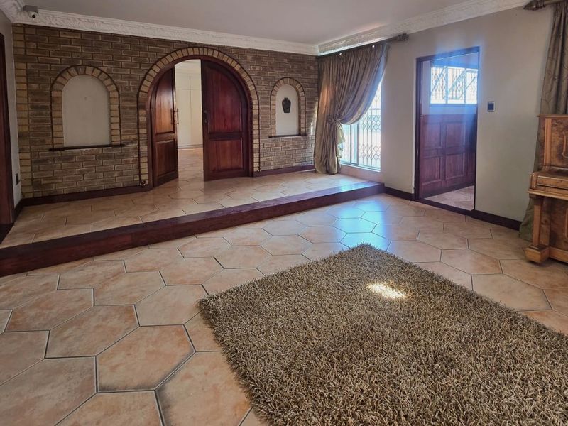 Spacious living area featuring unique hexagonal floor tiles, an exposed brick feature wall with arched doorways, and classic timber architectural detailing.