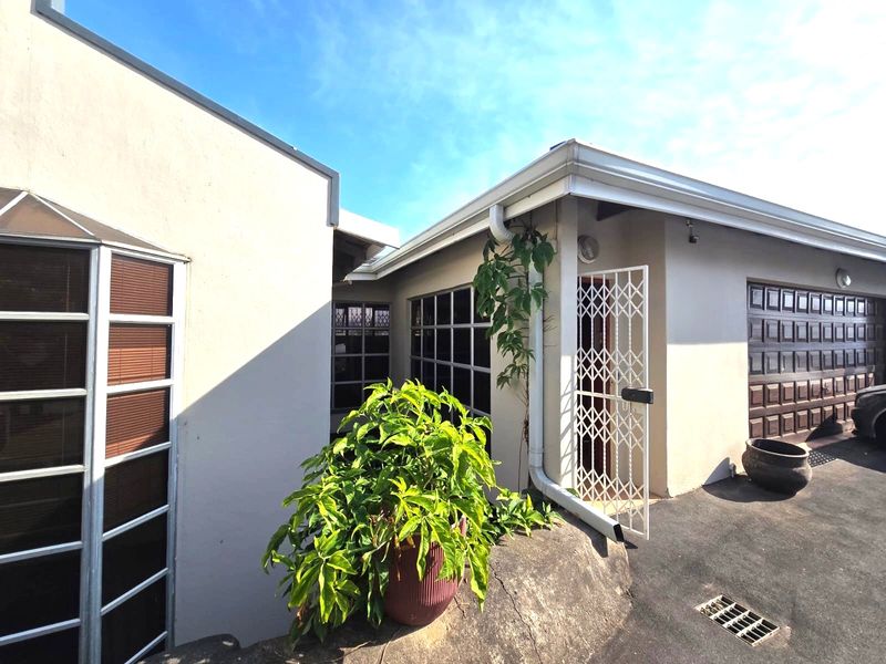 Exterior view of the property entrance featuring a security gate, garage access, and paved driveway area.