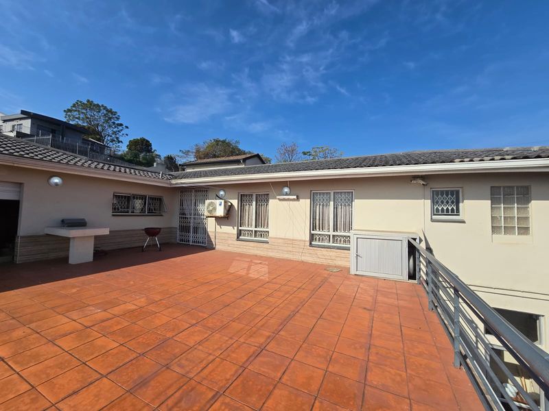 Spacious outdoor patio area featuring tiled flooring, a built-in concrete counter, and secure metal railings, ideal for outdoor entertaining.