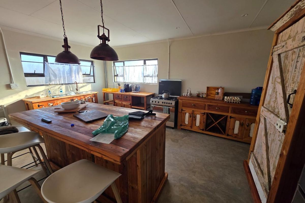 Rustic kitchen featuring a large wooden island, built-in cabinetry, gas stove, and concrete flooring with ample natural light.